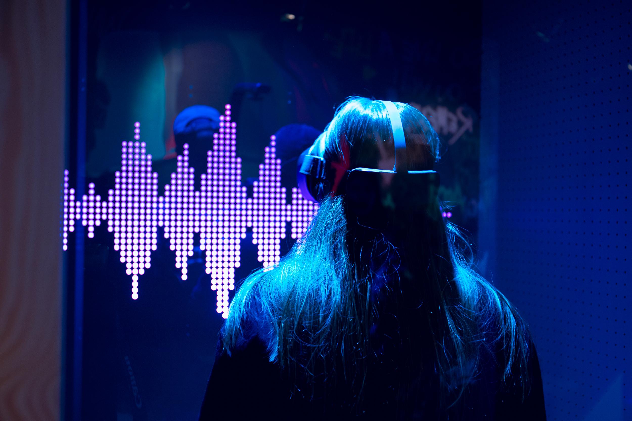 Person wearing VR in front of a vibrant digital soundwave display, showcasing cutting-edge digital technology in Stockholm