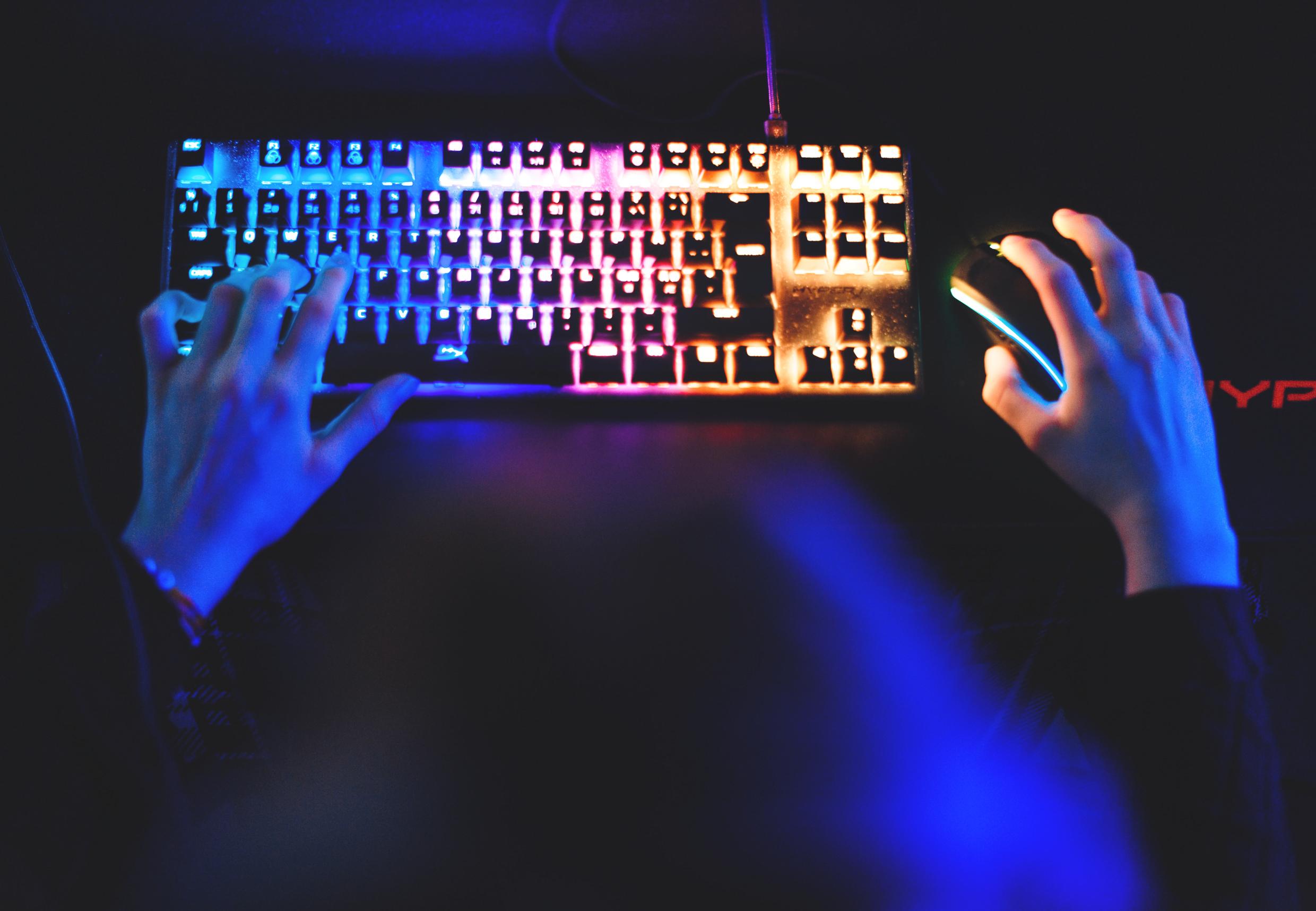 Close-up of hands on a colorful illuminated gaming keyboard and mouse, highlighting Stockholm’s thriving digital gaming and tech industry