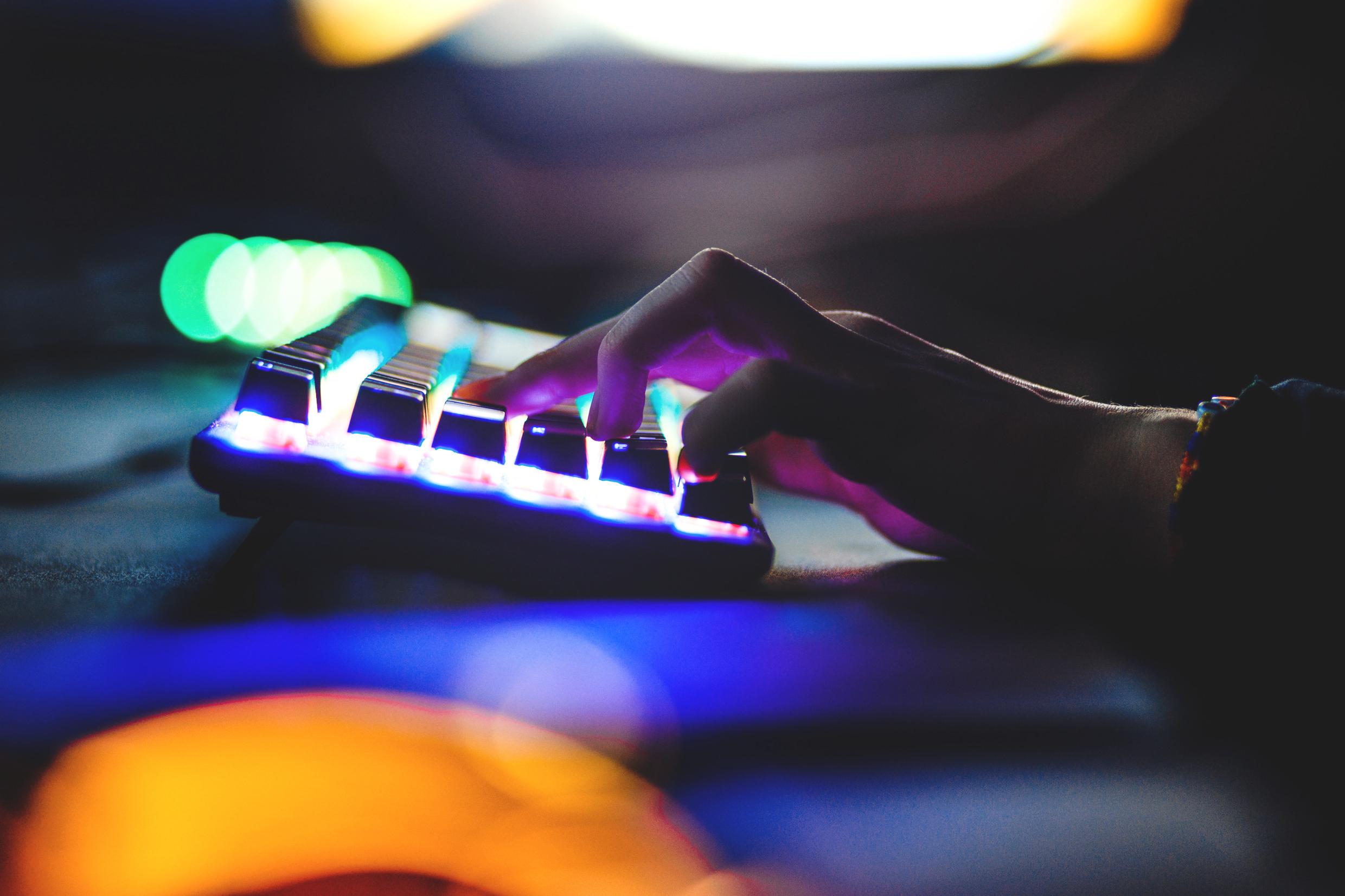 Close-up of a hand typing on a brightly lit mechanical keyboard, symbolizing Stockholm’s thriving digital gaming and tech industry.