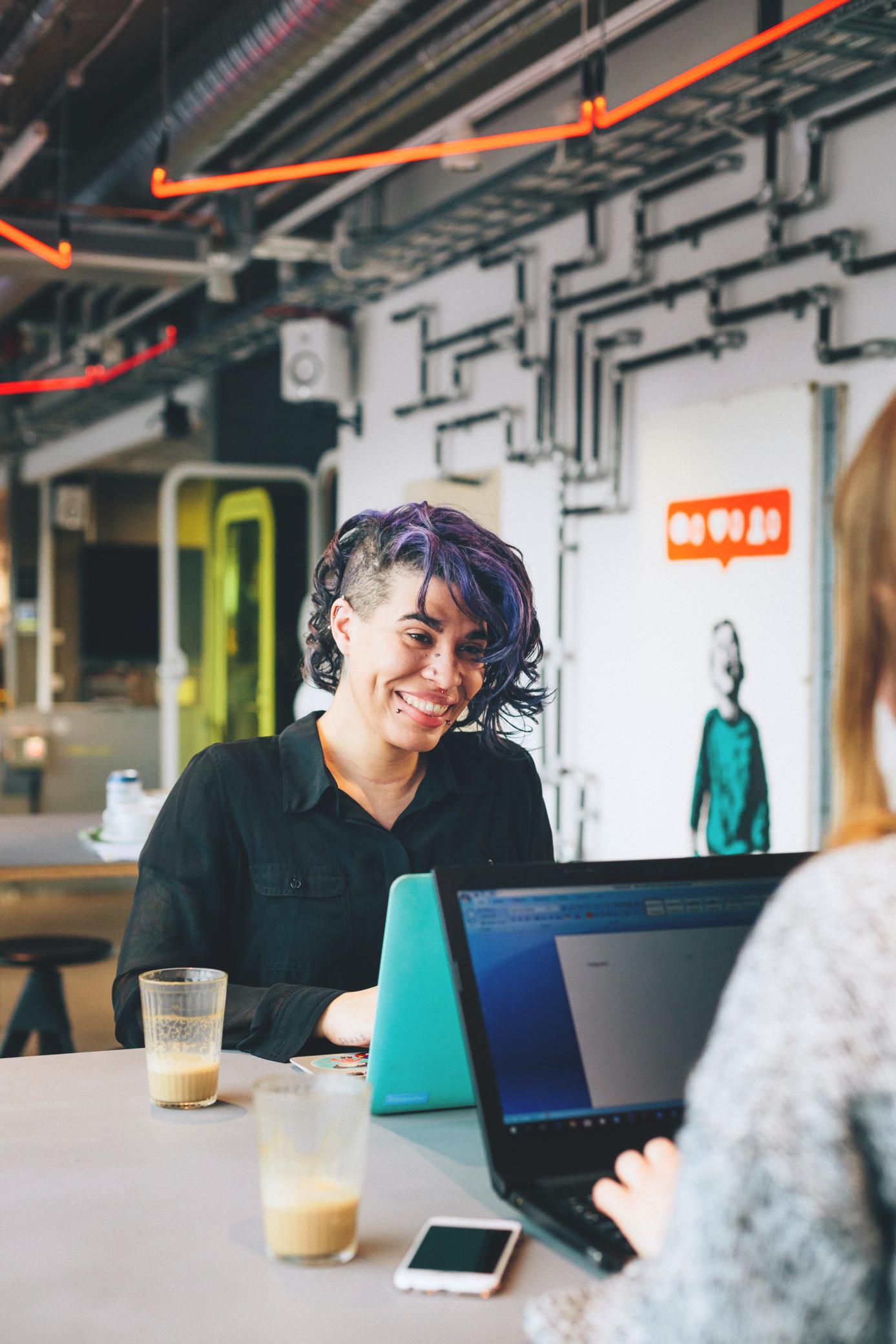Two professionals working together in a modern coworking space in Stockholm, with vibrant industrial decor and a focus on collaboration.