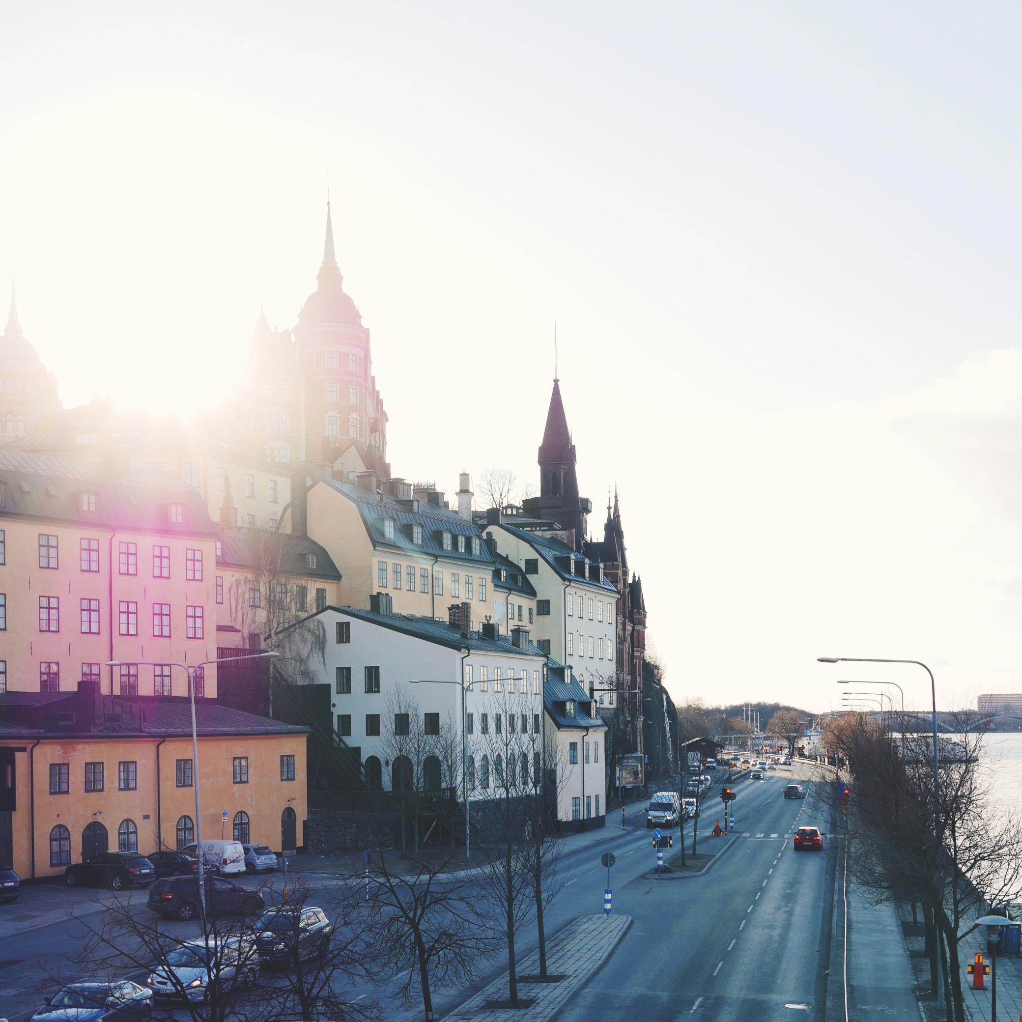 Scenic view of Stockholm’s historic buildings along a quiet street, with sunlight streaming over the skyline.