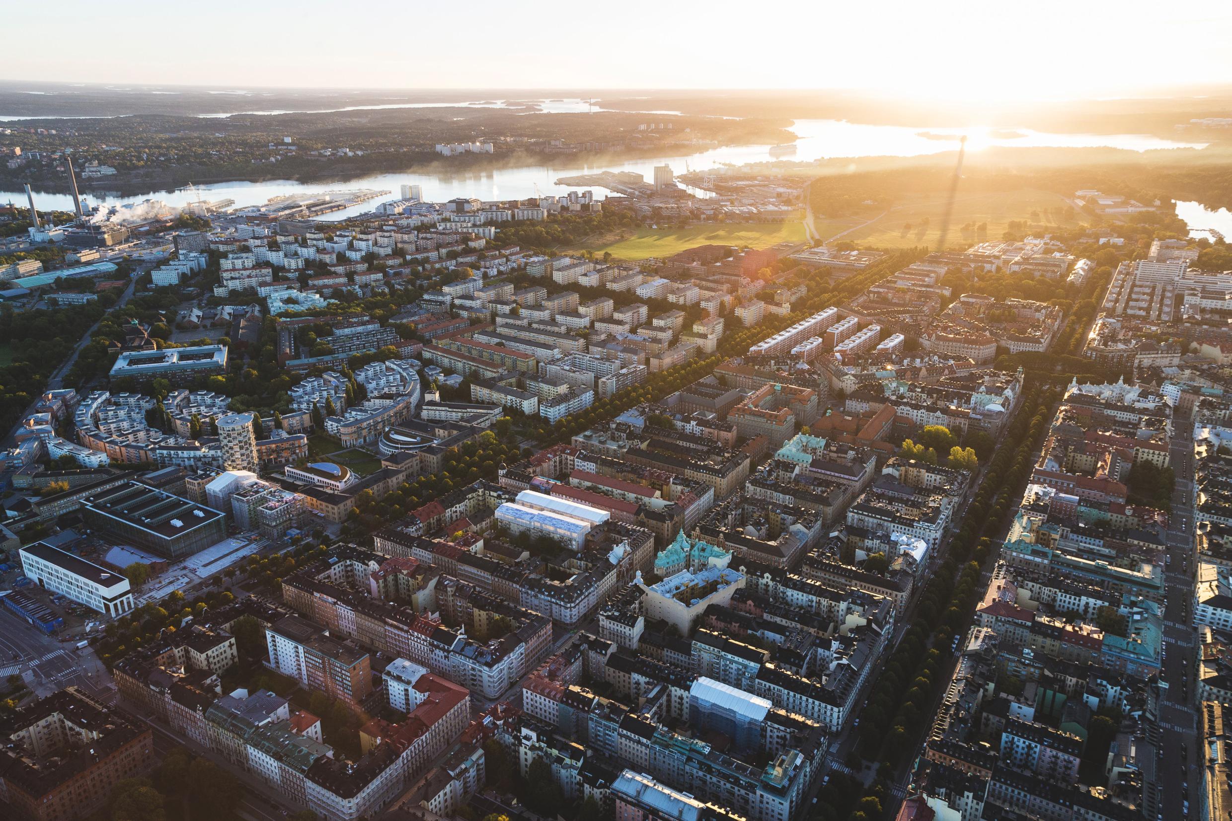Aerial view of Stockholm’s cityscape at sunrise, featuring residential neighborhoods, green spaces, and waterways highlighting sustainable urban planning.