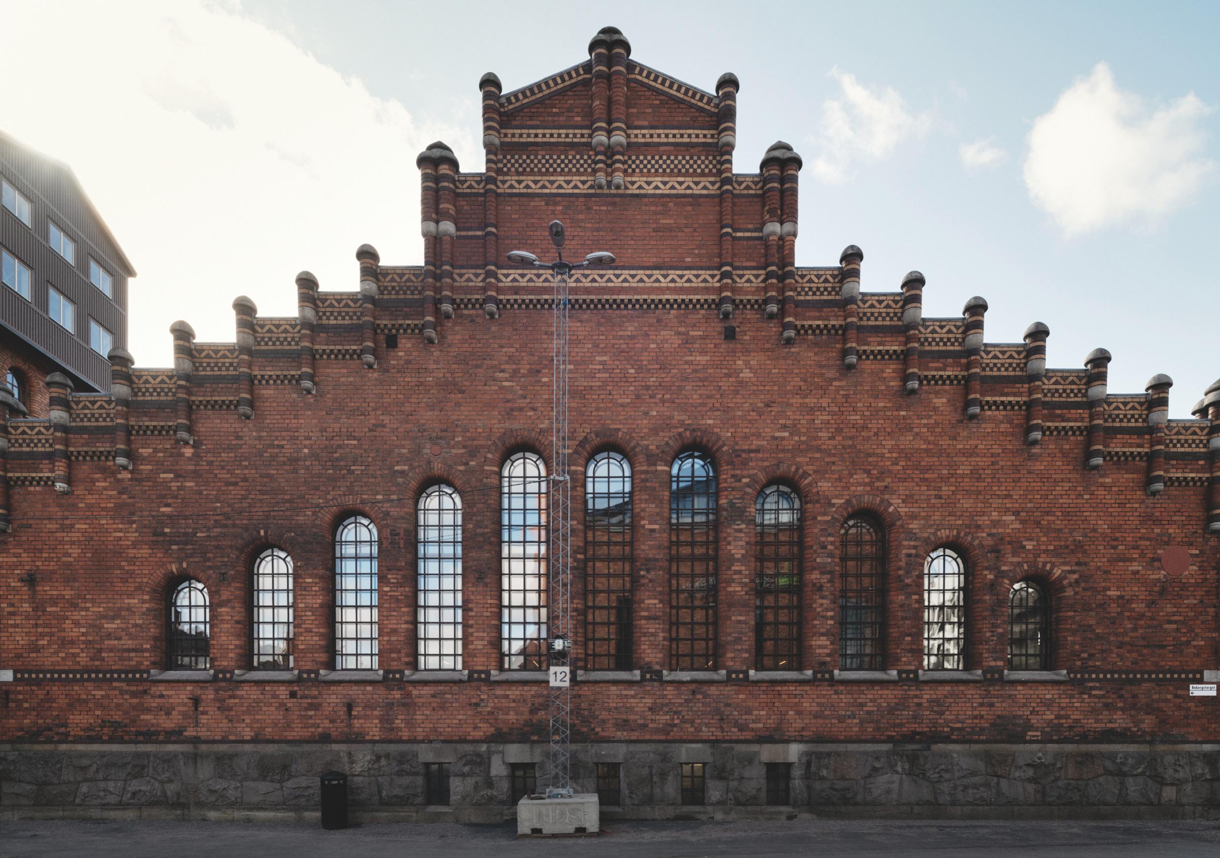 Historic red brick building with large arched windows in Stockholm, showcasing industrial architectural design.