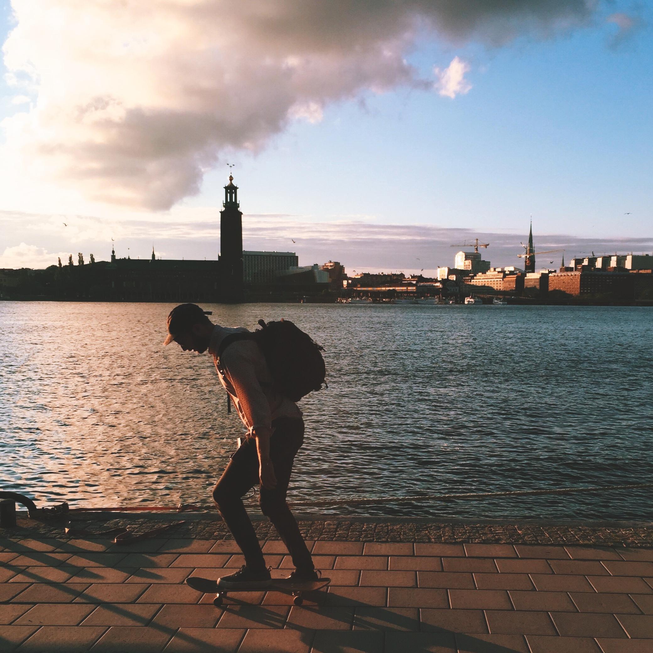 Skateboarder along Stockholm's waterfront, with the City Hall in the background